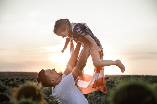 Una familia feliz con una bandera estadounidense al atardecer.