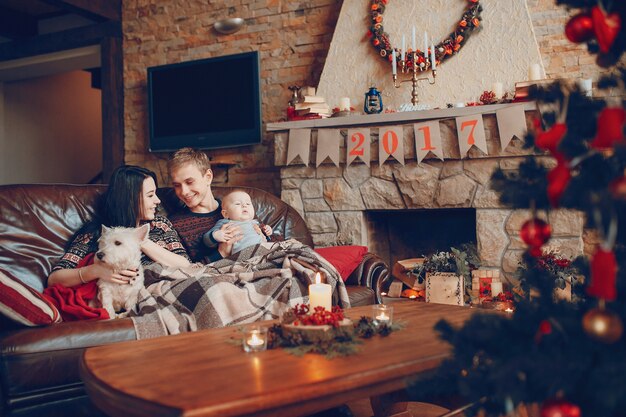 Familia feliz con un bebé y un perro y a su lado una chimenea con el cartel de 2017