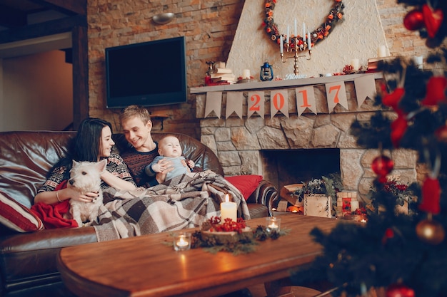Familia feliz con un bebé y un perro y a su lado una chimenea con el cartel de 2017