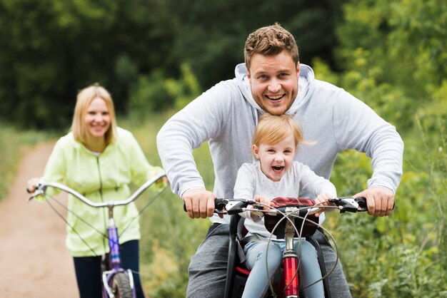 Familia feliz con bicicletas en camino forestal