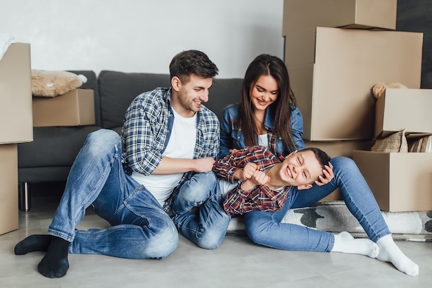 Familia feliz con cajas de cartón jugando con hijo