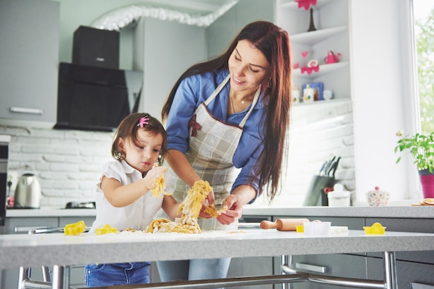 Familia feliz en la cocina. Madre e hija preparando la masa, hornear galletas.