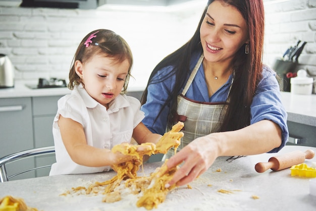 Familia feliz en la cocina. Madre e hija preparando la masa, hornear galletas.