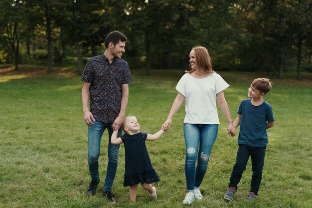 Familia feliz cogidos de la mano mientras camina por el parque