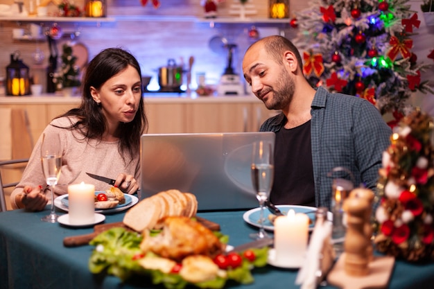 Familia feliz comiendo una deliciosa cena de Navidad sentado en la mesa de comedor