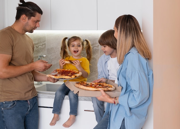 Familia feliz comiendo pizza en su nuevo hogar