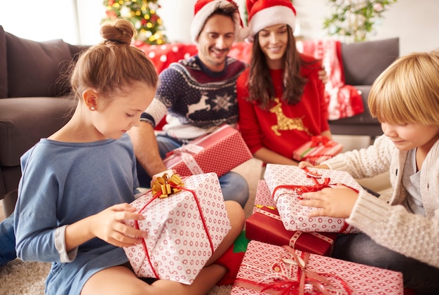 Familia feliz comienza a abrir regalos de Navidad