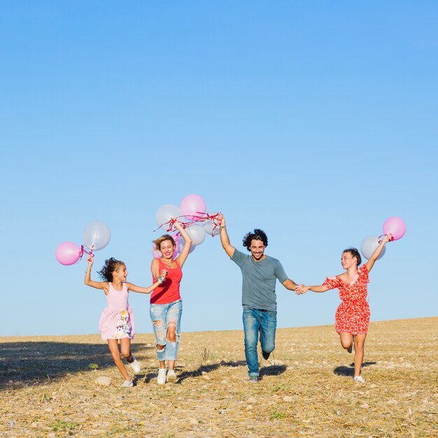 Familia feliz corriendo con globos