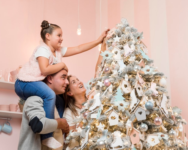 Familia feliz decorando el árbol de navidad