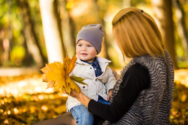 Familia feliz divirtiéndose al aire libre en el parque de otoño contra hojas borrosas