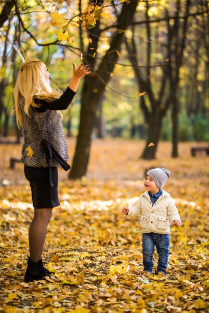 Familia feliz divirtiéndose al aire libre en el parque de otoño contra hojas borrosas