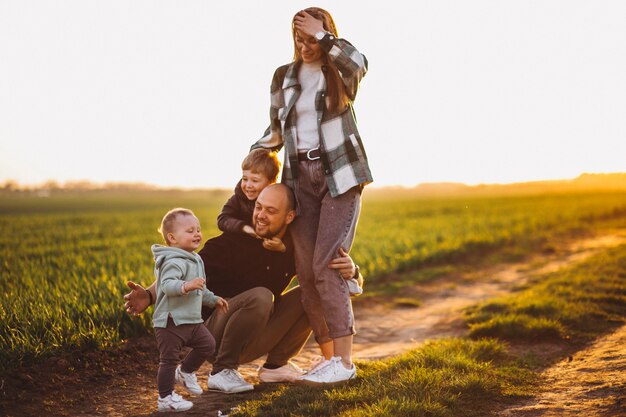 Familia feliz divirtiéndose en el campo en la puesta del sol