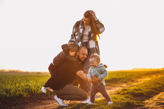 Familia feliz divirtiéndose en el campo en la puesta del sol