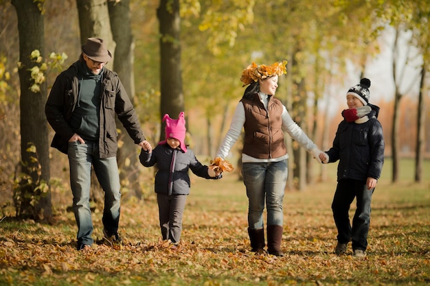 Familia feliz divirtiéndose durante el follaje Los padres y sus hijos caminando en el bosque de otoño todos juntos y riendo