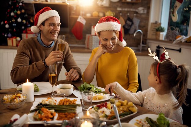 Familia feliz divirtiéndose mientras habla durante el almuerzo de Navidad en el comedor
