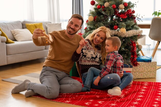 Familia feliz divirtiéndose y posando junto al árbol de Navidad