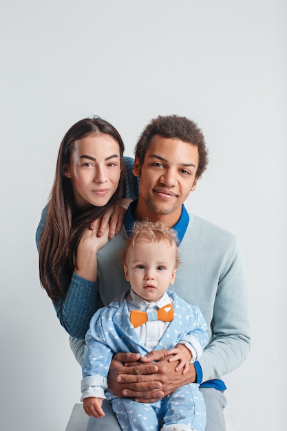 Una familia feliz de hombre afro y mujer caucásica y niño en estudio blanco