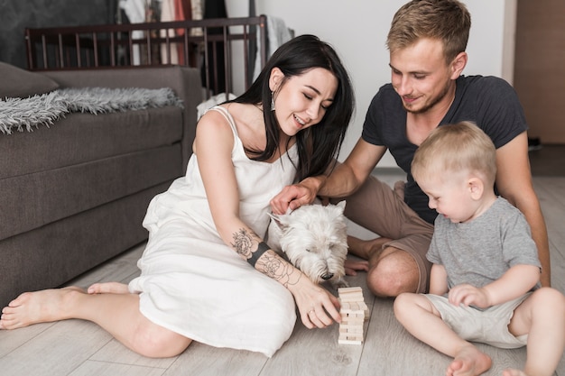 Familia feliz jugando a bloques de madera juego de torre con perro