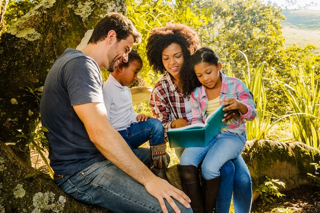 Familia feliz leyendo juntos debajo de un árbol