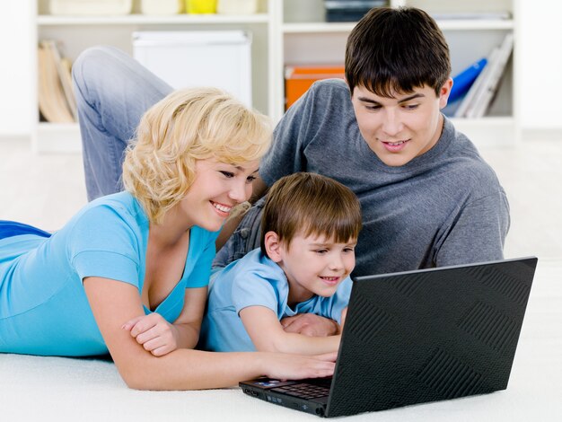 Familia feliz mirando juntos en la computadora portátil