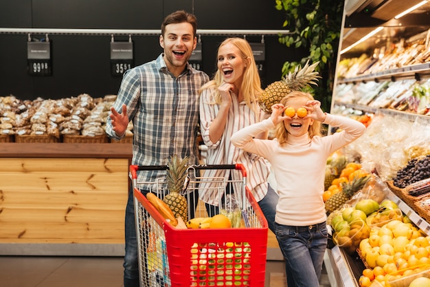 Familia feliz con niño comprando comida en la tienda de comestibles