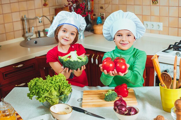 Familia feliz niños divertidos están preparando una ensalada de verduras frescas en la cocina