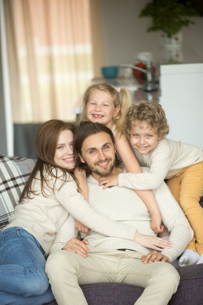 Familia feliz con los niños en el sofá mirando a la cámara, retrato