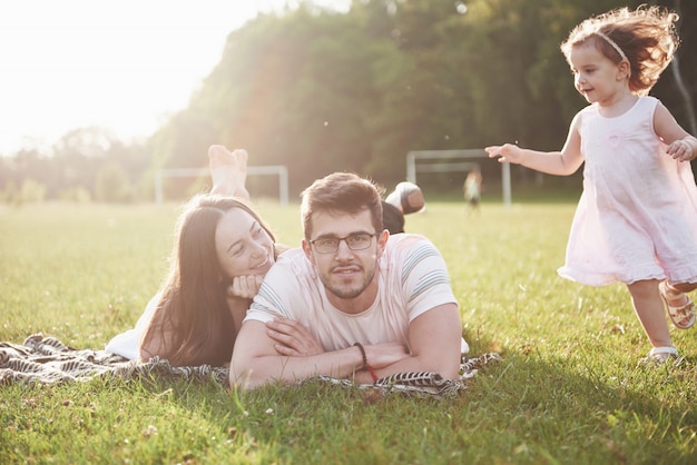 Familia feliz, padre de madre e hija de bebé en la naturaleza al atardecer