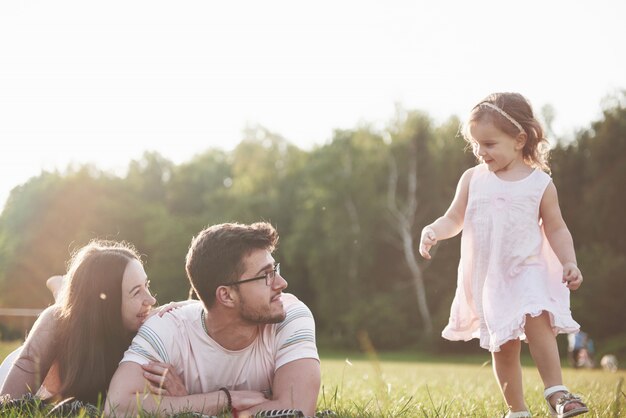 Familia feliz, padre de madre e hija de bebé en la naturaleza al atardecer