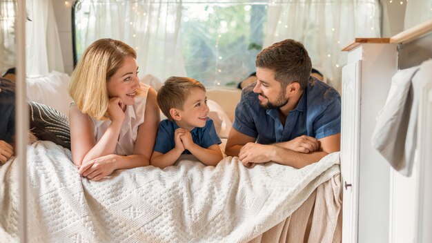 Familia feliz pasar tiempo en la cama en una caravana