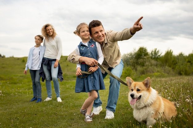Familia feliz con perro en la naturaleza tiro completo