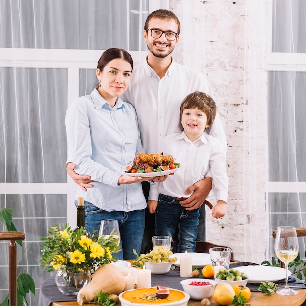 Familia feliz con pollo al horno en la mesa