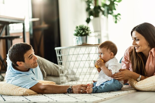 Familia feliz relajándose en el suelo y divirtiéndose juntos en la sala de estar