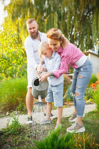 Foto gratuita familia feliz durante el riego de plantas en un jardín al aire libre