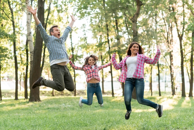 Familia feliz saltando en la naturaleza verde