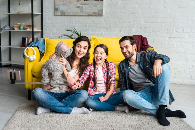 Familia feliz sentada en un piso tomando una selfie