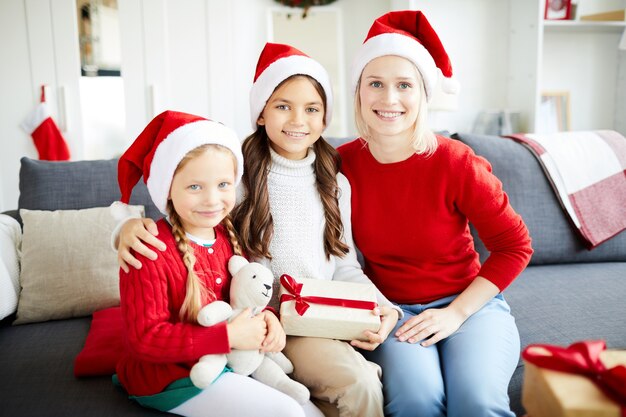 Familia feliz sentado en el sofá y desenvolver regalos de Navidad