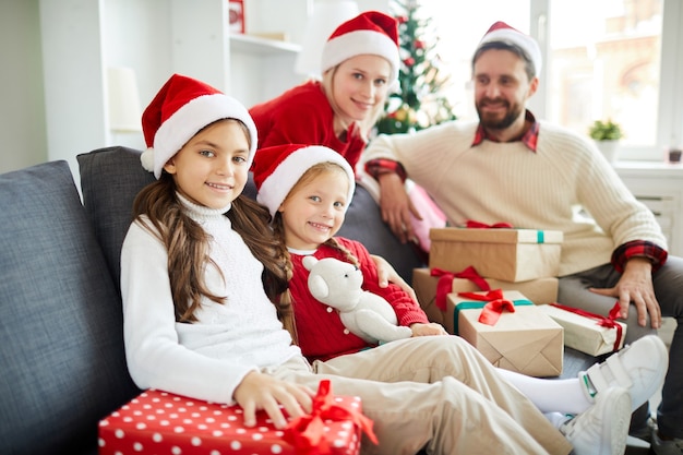 Familia feliz sentado en el sofá con regalos de Navidad