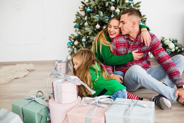 Familia feliz sentados enfrente de árbol de navidad