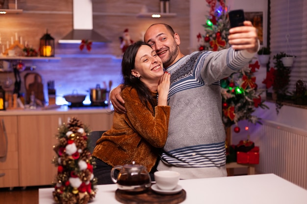 Familia feliz sonriendo mientras toma selfie con smartphone moderno