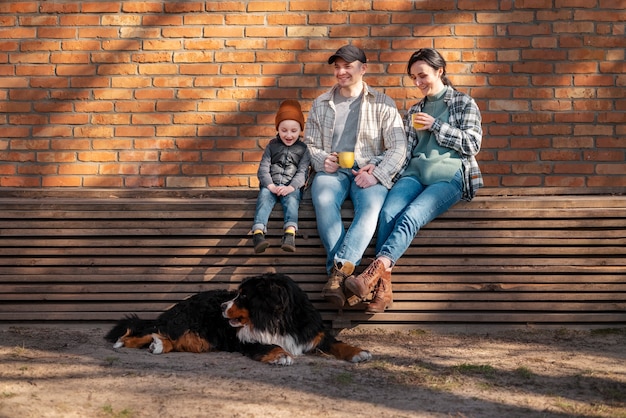 Foto gratuita familia feliz de tiro completo sentada afuera