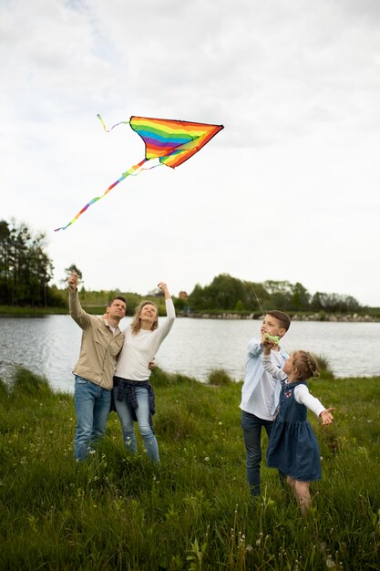 Familia feliz de tiro completo volando cometa colorida