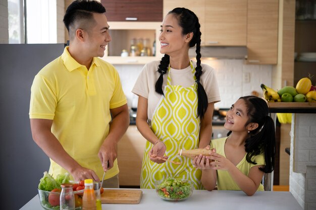 Familia feliz de tiro medio en la cocina