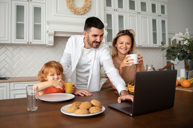 Familia feliz de tiro medio con laptop