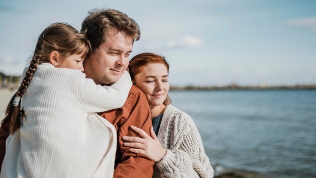 Familia feliz de tiro medio en la playa