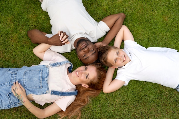 Familia feliz de tiro medio tendido sobre el césped