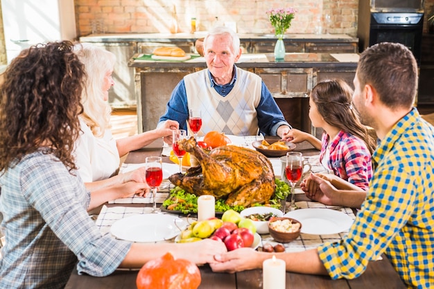 Familia feliz tomados de la mano en la mesa con la comida