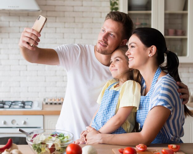 Familia feliz tomando selfie en cocina