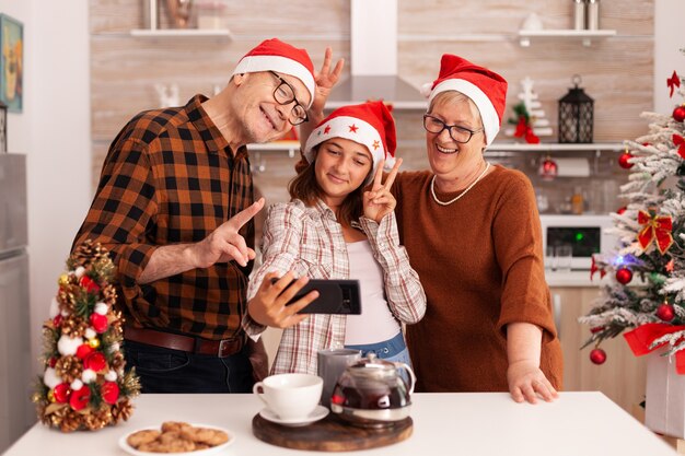 Familia feliz tomando selfie con smartphone haciendo expresiones divertidas