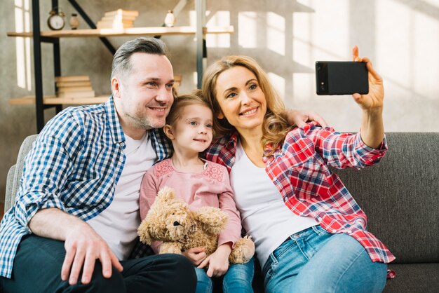 Familia feliz tomando selfie en el sofá